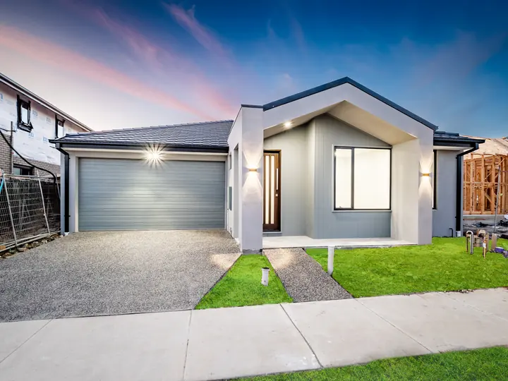 The facade with wall lights on at dusk, in the Aspen 25, built by Oakview at Oak Grove, Clyde North
