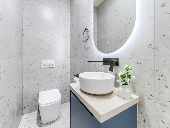 Ensuite with terrazzo-look tiles and a backlit round mirror, in a family home Oakview built in Clyde North