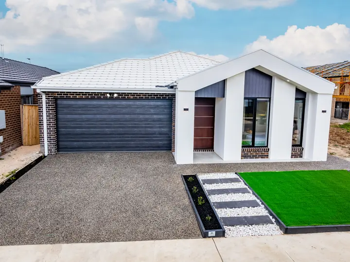 Gable facade with black cladding, a timber door and a stone path, in a family home Oakview built in Clyde North