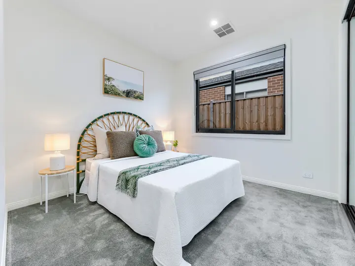 Guest bedroom with a rattan bedhead, in a family home Oakview built in Clyde North