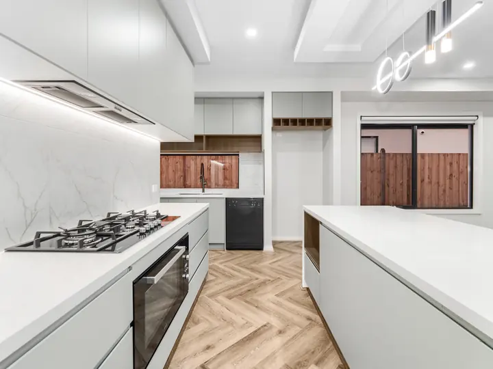 Gas cooktop, stone benchtops and a lit rangehood, in a single-storey home Oakview built in Clyde North