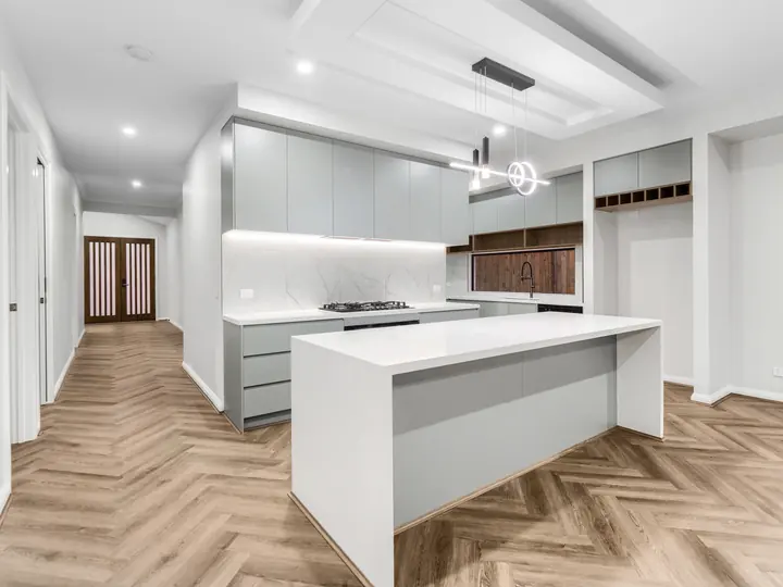 Kitchen island and dining space under a lit bulkhead, in a single-storey home Oakview built in Clyde North