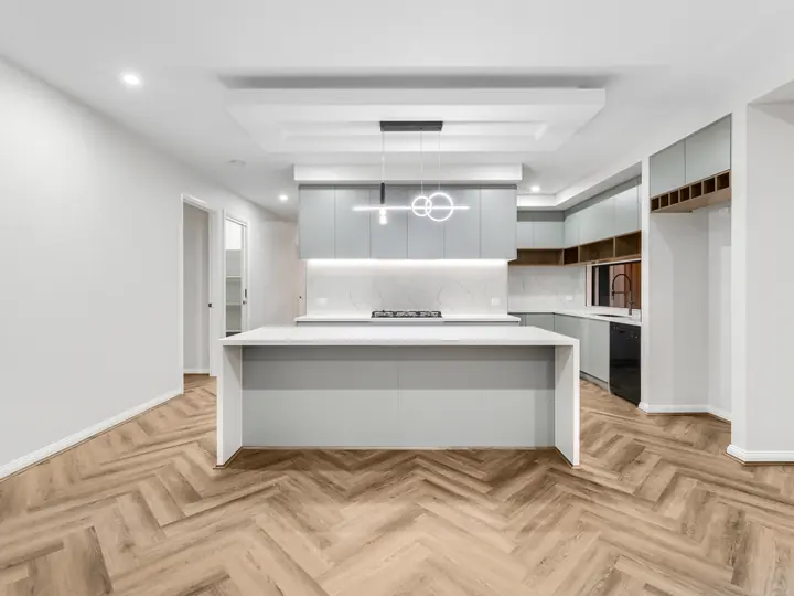Open kitchen with a stone island and ring pendant light, in a single-storey home Oakview built in Clyde North