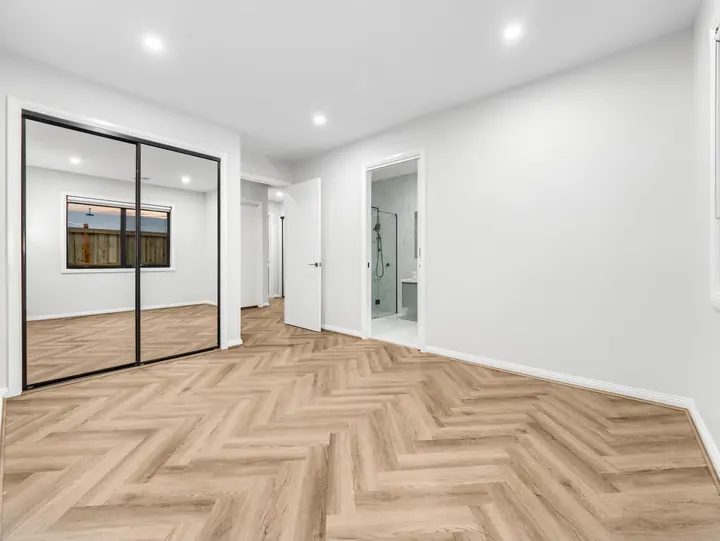 Bedroom with mirrored sliding robe doors, in a single-storey home Oakview built in Clyde North