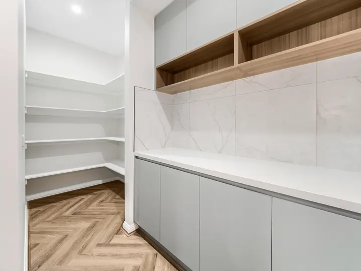 Walk-in pantry with open shelving and stone benchtops, in a single-storey home Oakview built in Clyde North