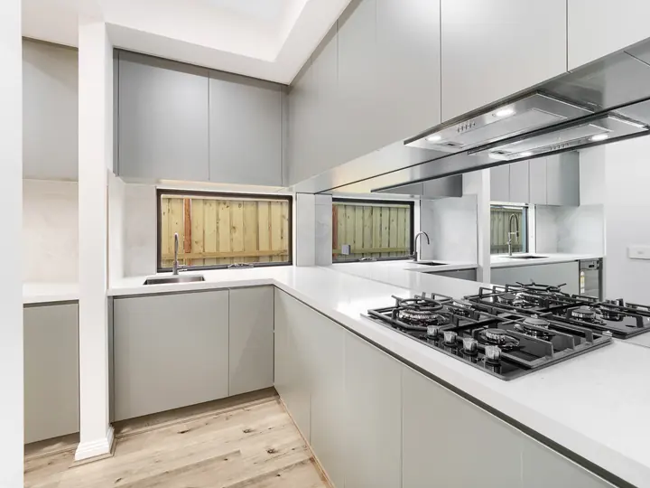 Gas cooktop and stone benchtops in the kitchen, in a custom home Oakview finished in brushed gold fittings