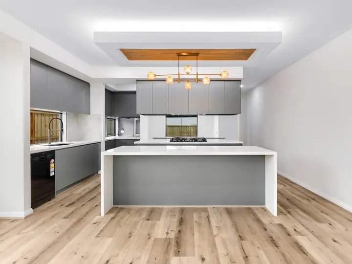 Kitchen with a stone island under a timber-batten bulkhead, in a custom home Oakview finished in brushed gold fittings