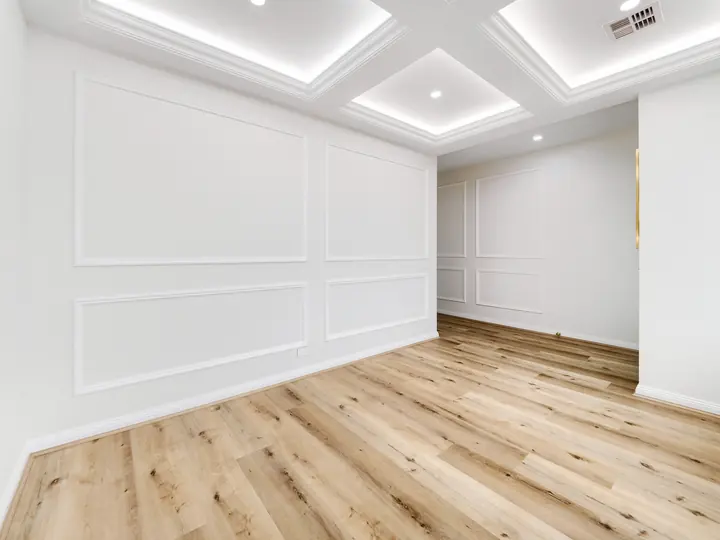 Room with panelled walls and a coffered ceiling, in a custom home Oakview finished in brushed gold fittings