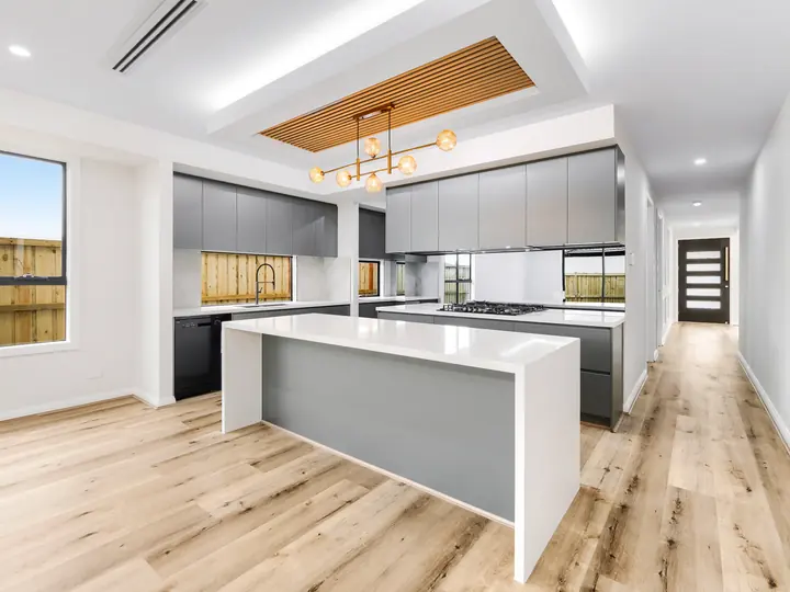 Gold pendant light over the kitchen island, in a custom home Oakview finished in brushed gold fittings