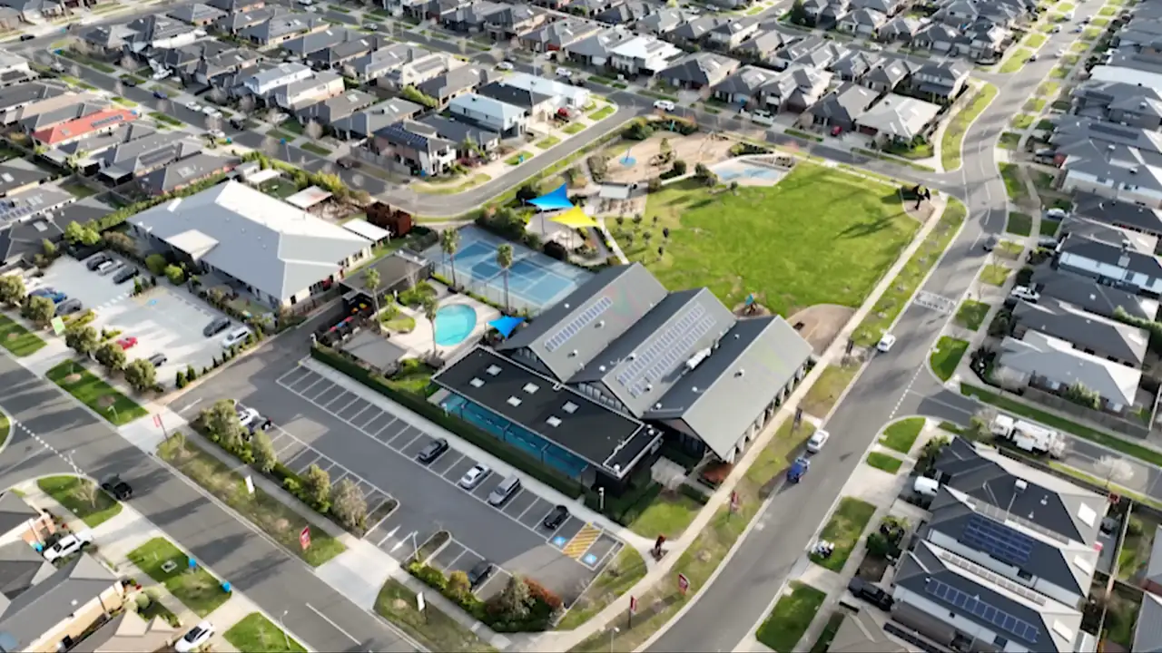 Aerial view over a park, a pool and new streets in Clyde North